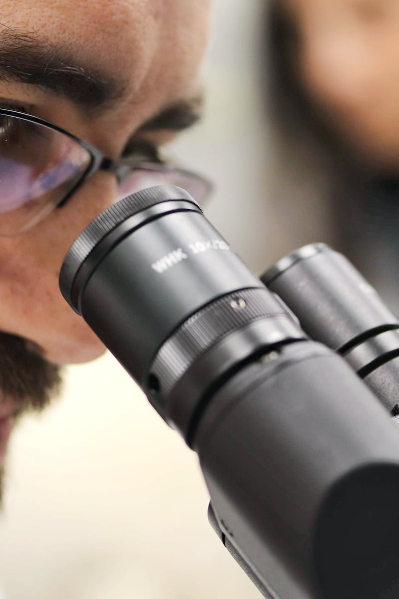 Close-up of a scientist examining samples using a microscope in a laboratory setting.